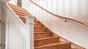 A wooden staircase with white railings and a handrail.