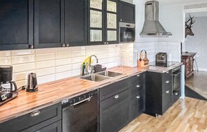 A modern kitchen with black cabinets, a wooden countertop, a dishwasher, and a large stove. - 5 bedroom lovely home in Ruda (Ruda)