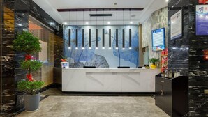 A reception desk with a marble counter, potted plants, and a wall mural. - Lifeng Tangguo Hotel (Jinhua)
