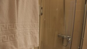 Ein Badezimmer mit Dusche und einem Handtuch, das an der Wand hängt.