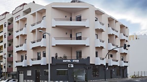 Ein mehrstöckiges Hotel mit Balkonen, einem gut sichtbaren Schild mit der Aufschrift 'HOTEL STAR' und einem modernen architektonischen Design.