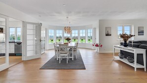 A spacious living area with a dining table and chairs, large windows, and a view of the outdoors. - 6 bedroom cozy home in Grindsted (Grindsted)
