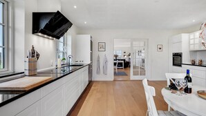 A modern kitchen with white cabinetry, a black countertop, and a central island. - 6 bedroom cozy home in Grindsted (Grindsted)