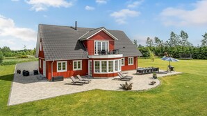 A red house with a large patio, outdoor furniture, and a windmill in the background. - 6 bedroom cozy home in Grindsted (Grindsted)