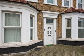 A row of terraced houses with white-framed windows and doors, brick walls, and a tiled roof.