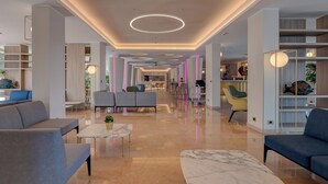 Un'ampia hall con pavimento in marmo, sedute moderne e un'area reception centrale.