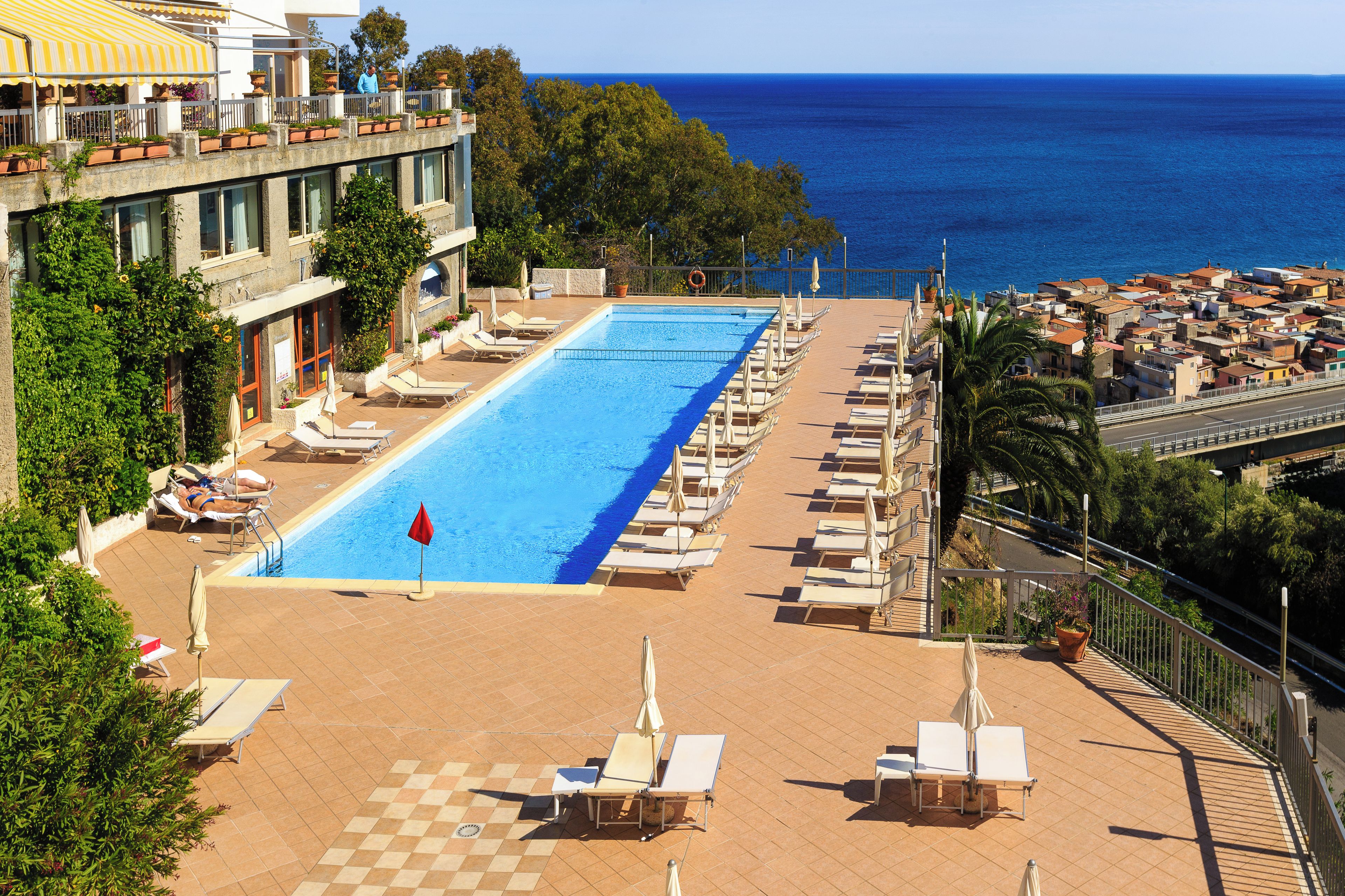 Zona de piscina con sillones de descanso y vista al mar.