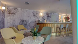 Un espace bar moderne avec une table au plateau en marbre, des tabourets de bar et une plante décorative.