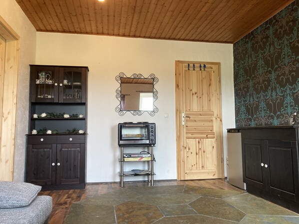 Una cocina con armarios de madera oscura, suelo de baldosas de piedra, una puerta de madera y un espejo decorativo.