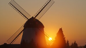 Silhouet van een windmolen voor een ondergaande zon.