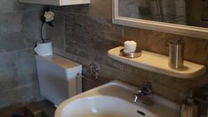 Een badkamer met een wit wastafel, een spiegel, een toilet en een kastje.