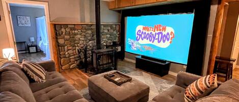 Un salón acogedor con chimenea de piedra, un televisor de pantalla plana grande y asientos cómodos.