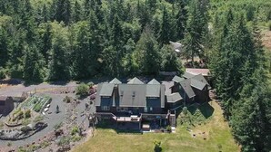 A large, multi-story lodge with a prominent roofline, surrounded by dense forest and mountains in the background.