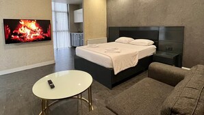 A modern bedroom with a bed, a TV, a sofa, and a small table. - Kent Suites Hotels (Istanbul)