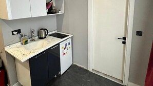 A compact kitchen with a sink, stove, and cabinets. - Kent Suites Hotels (Istanbul)
