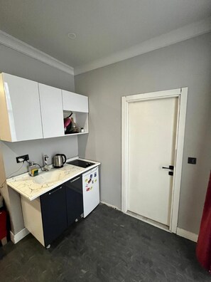 A compact kitchen with a sink, stove, and cabinets.