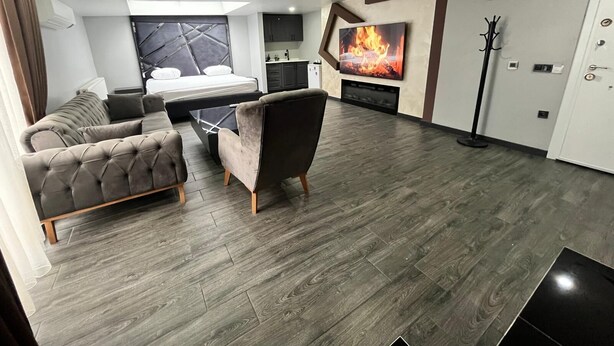 A modern living room with a sofa, armchair, and a flat-screen TV mounted on the wall. - Kent Suites Hotels (Istanbul)
