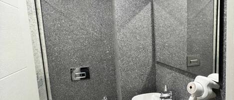 Une petite salle de bain avec des toilettes blanches, un lavabo avec un miroir et un sèche-cheveux.