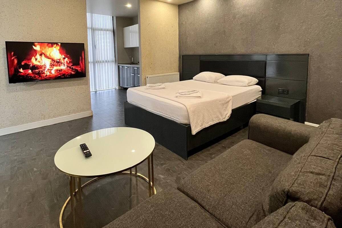 A modern bedroom with a bed, a TV, a sofa, and a small table.