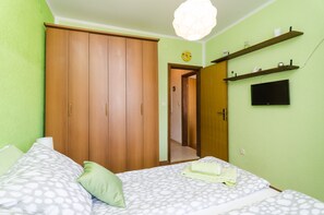 Ein Schlafzimmer mit zwei Betten, einem Kleiderschrank, einem Fernseher und einem Regal mit Dekoration.