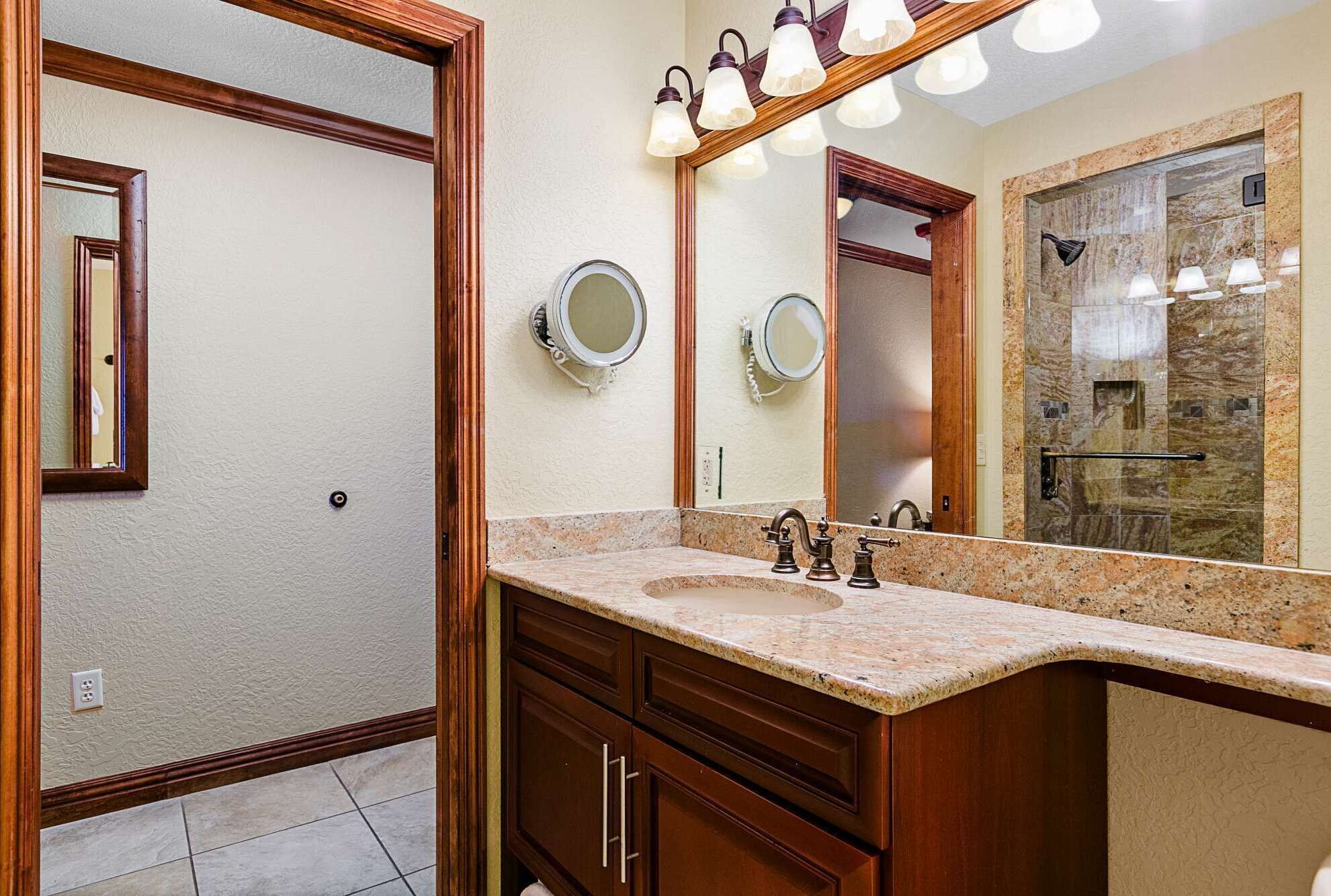 A bathroom with a vanity, two mirrors, and a shower area.