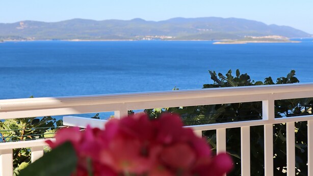 Un balcón con vista al mar y montañas a lo lejos.