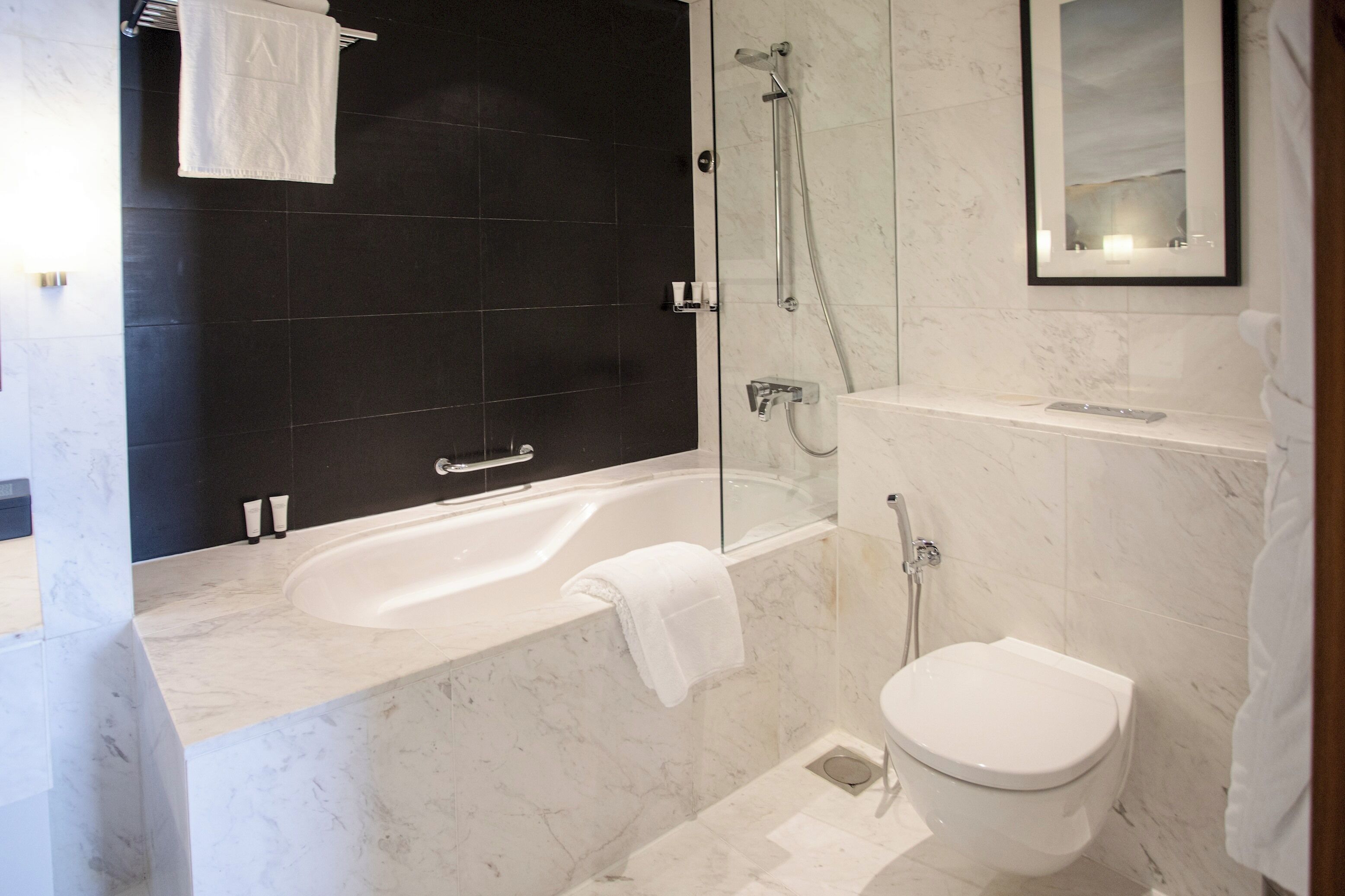 A modern bathroom with a bathtub, shower, and toilet.