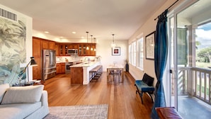 A spacious living area with a kitchen, a dining area, and a balcony with a view.