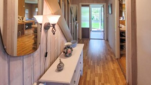 A hallway with wooden flooring, a white console table with a decorative vase, and a wall-mounted light fixture. - Gorgeous home in Reksteren with kitchen (Reksteren)
