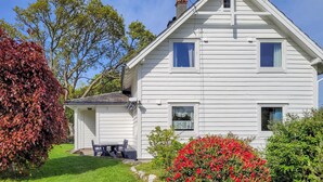 A white two-story house with a covered porch and a small table and chairs. - Gorgeous home in Reksteren with kitchen (Reksteren)