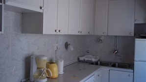Une cuisine avec des meubles blancs, un plan de travail, une machine à café, un grille-pain et un évier.