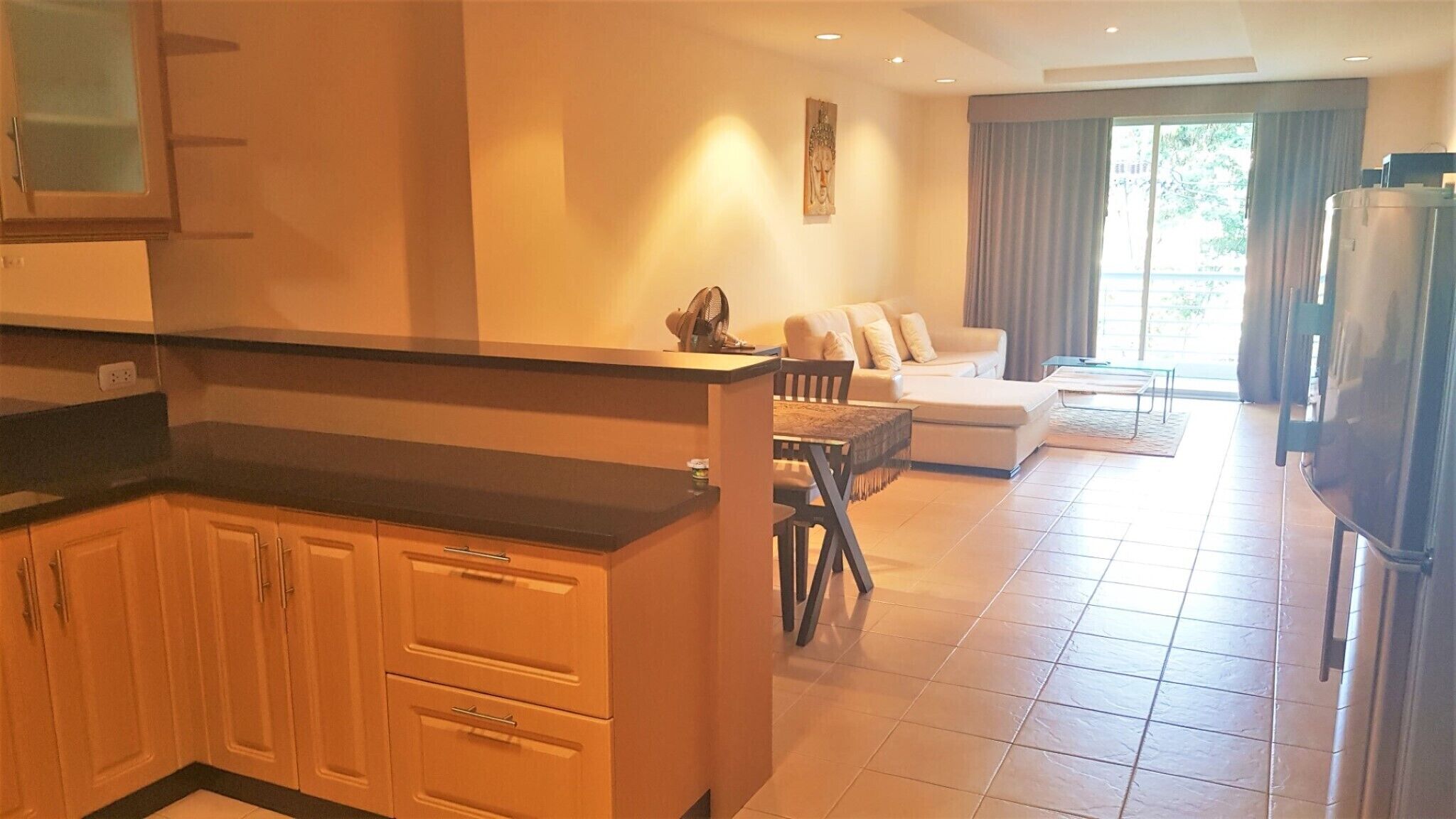 A compact kitchen with a dining area, a sofa, and a large window.