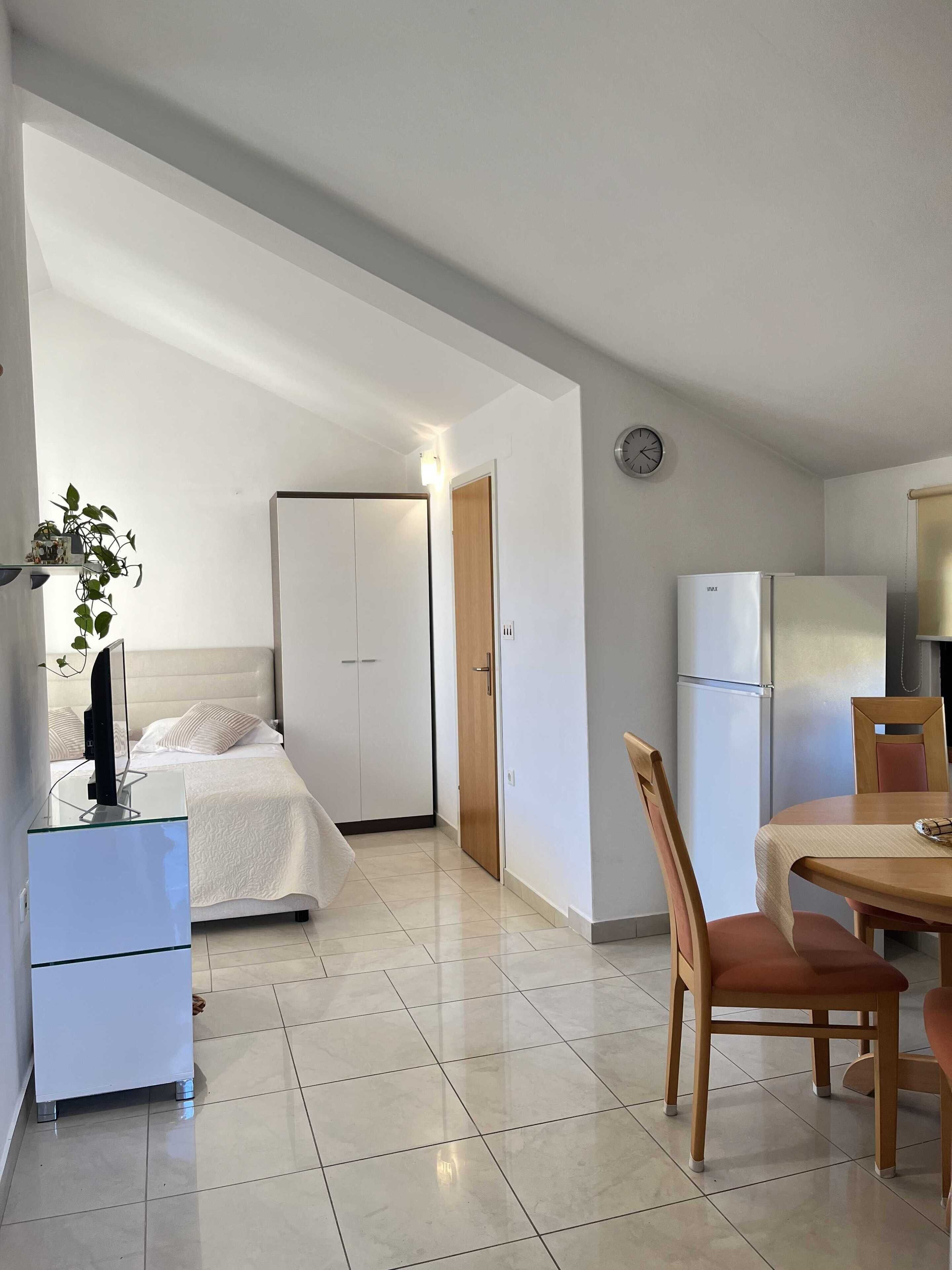 Une chambre moderne avec un lit, une table de chevet et un téléviseur. Il y a également un petit coin repas avec une table et des chaises.