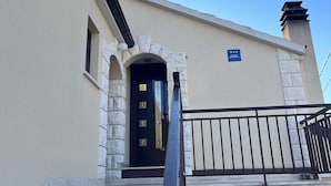A building with a black door, stone steps, and a metal railing.