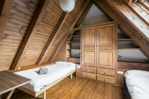 Une pièce en bois avec un lit en mezzanine, une commode en bois et un banc.