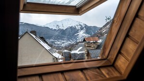 Vista desde una ventana de madera con una montaña nevada al fondo.
