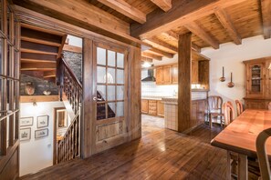 Un intérieur en bois avec un escalier menant à un deuxième étage, un coin repas avec une table en bois et des meubles de cuisine.