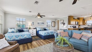 A spacious bedroom with two beds, a blue sofa, and a kitchen area.