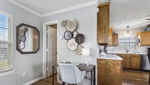 A modern kitchen with wooden cabinets, a central island, and a dining area with a table and chair.