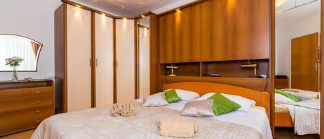 A bedroom with a large bed, wooden wardrobe, and a mirror.