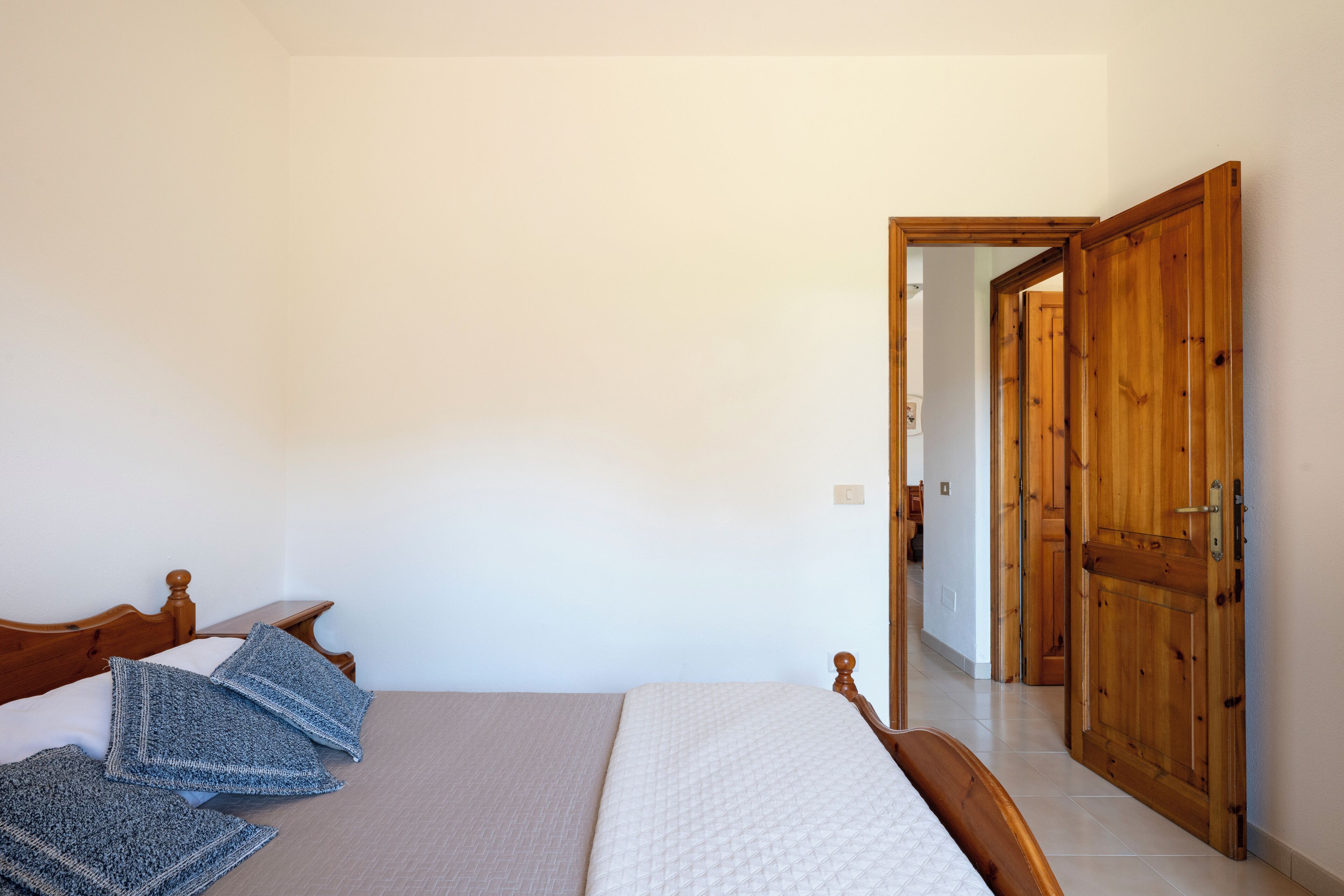 A bedroom with a wooden bed, a bedside table, and a large wooden door.