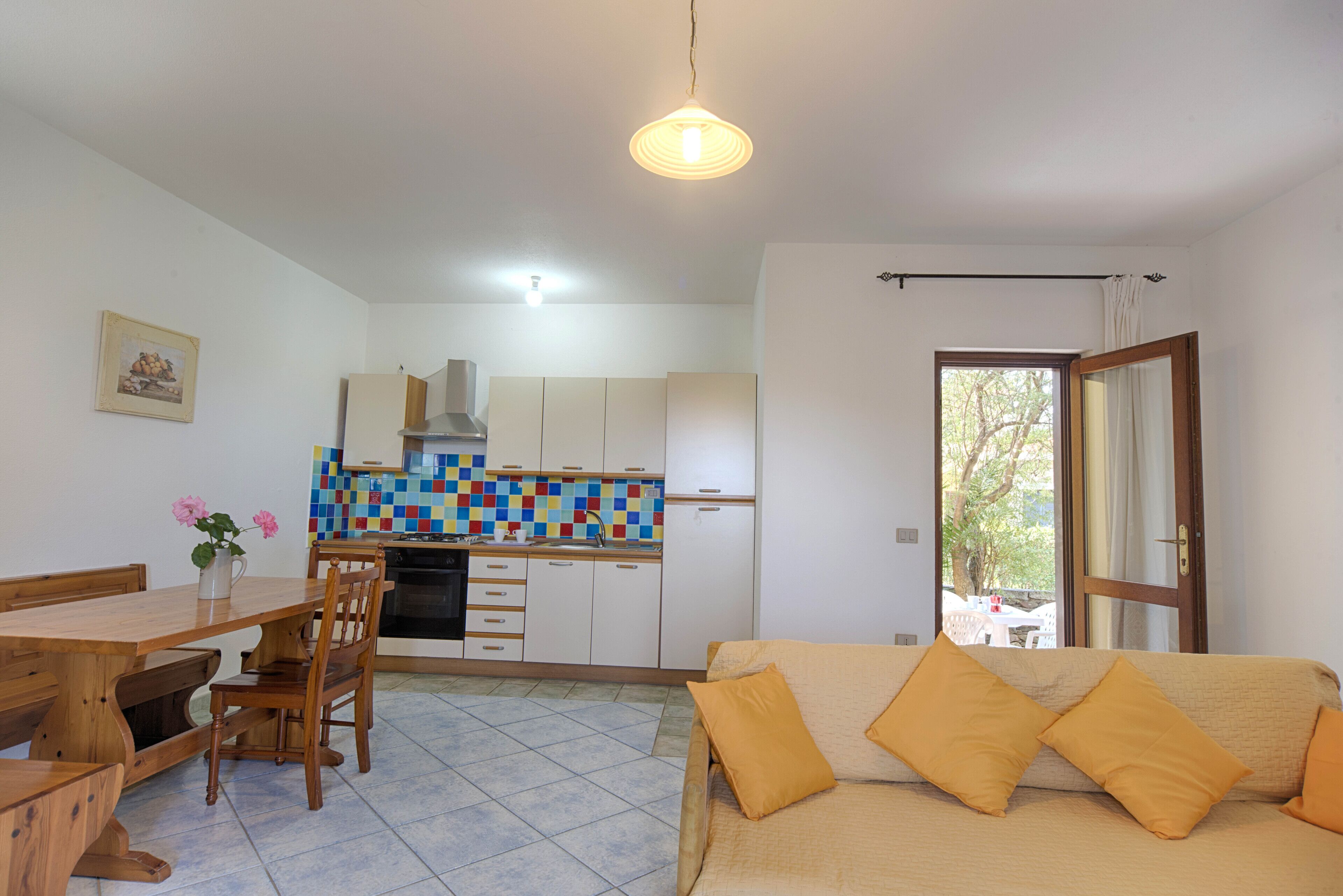 A compact living space with a dining area, kitchenette, and a sofa with cushions.