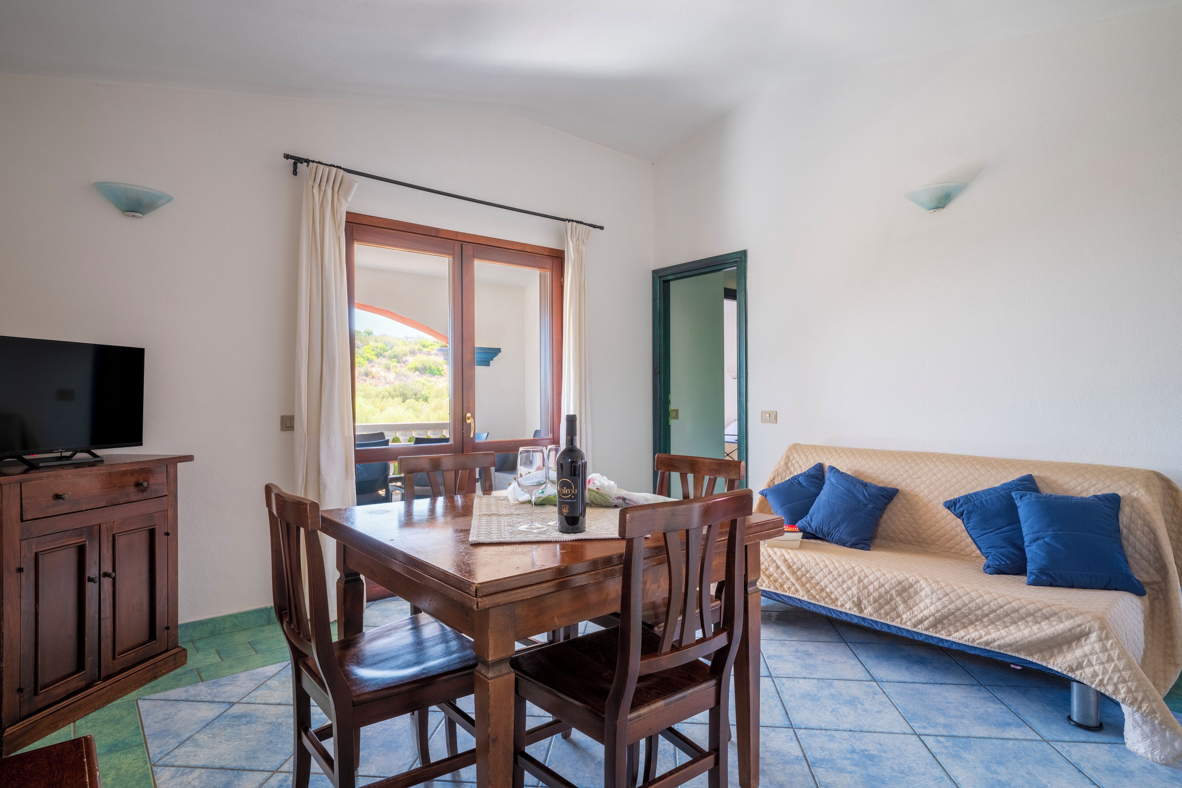 Un coin repas avec une table en bois, des chaises et un téléviseur posé sur un meuble.