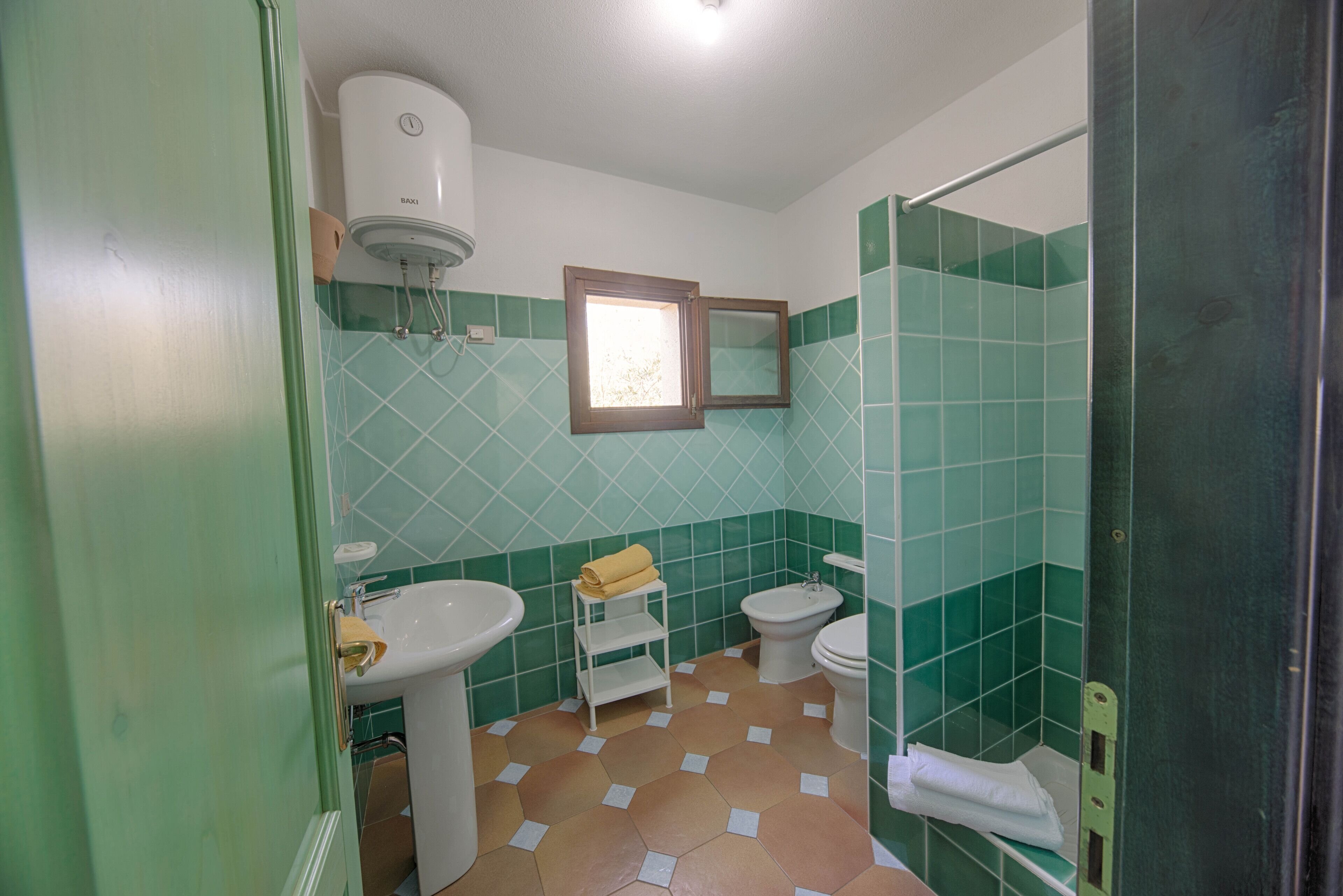 A bathroom with a sink, toilet, bidet, and a shower area.