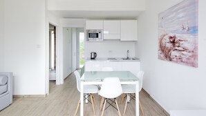 Una cocina moderna con armarios blancos, una mesa de comedor de vidrio y sillas blancas.