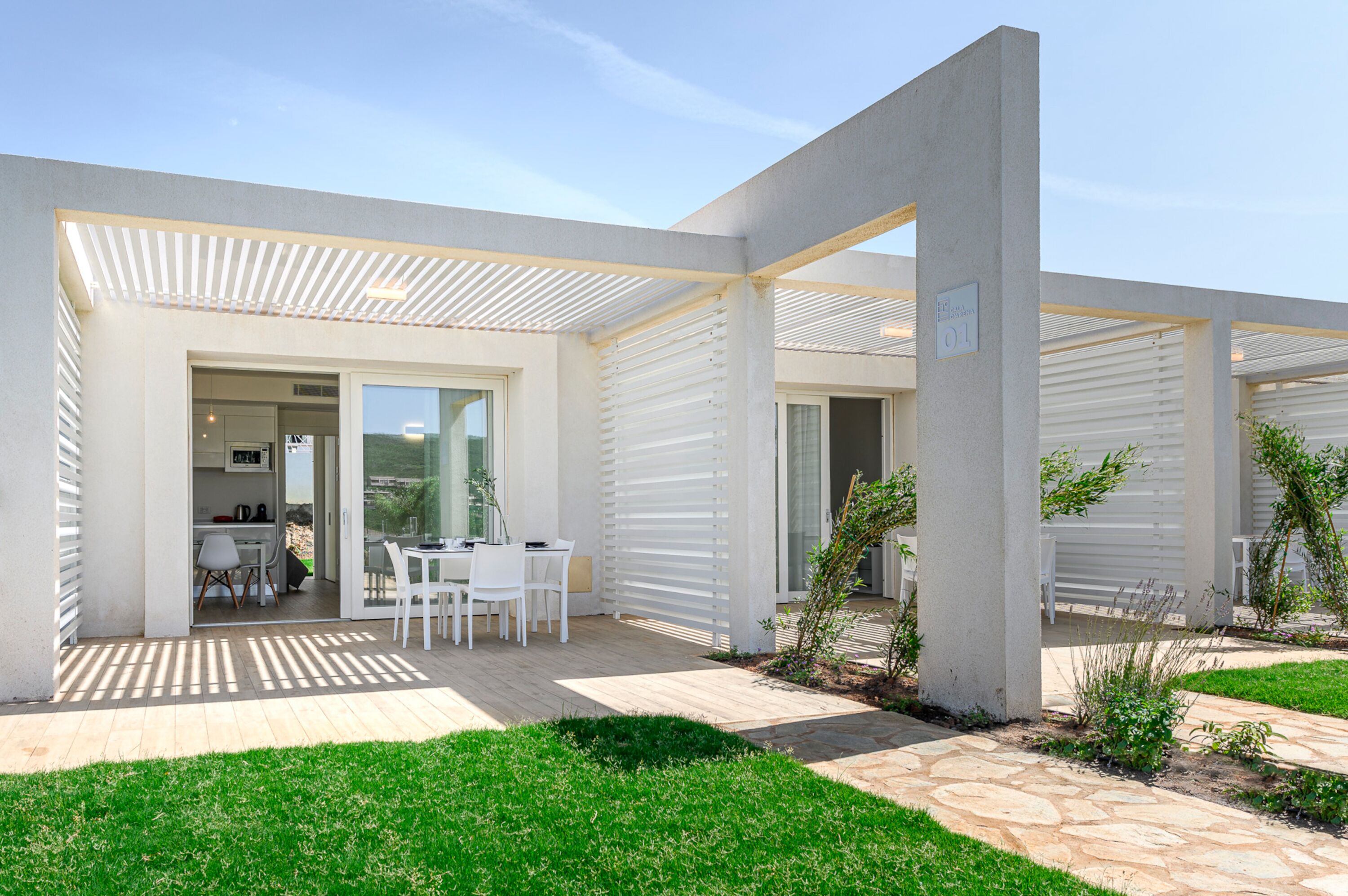Une maison moderne dotée d’un patio, d’une table à manger et de chaises.