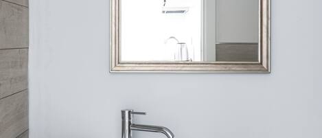 A bathroom with a white sink, a large mirror, and a towel rack with folded towels.