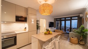 Una cocina moderna con una isla central, un comedor con mobiliario de mimbre y un balcón con vistas.