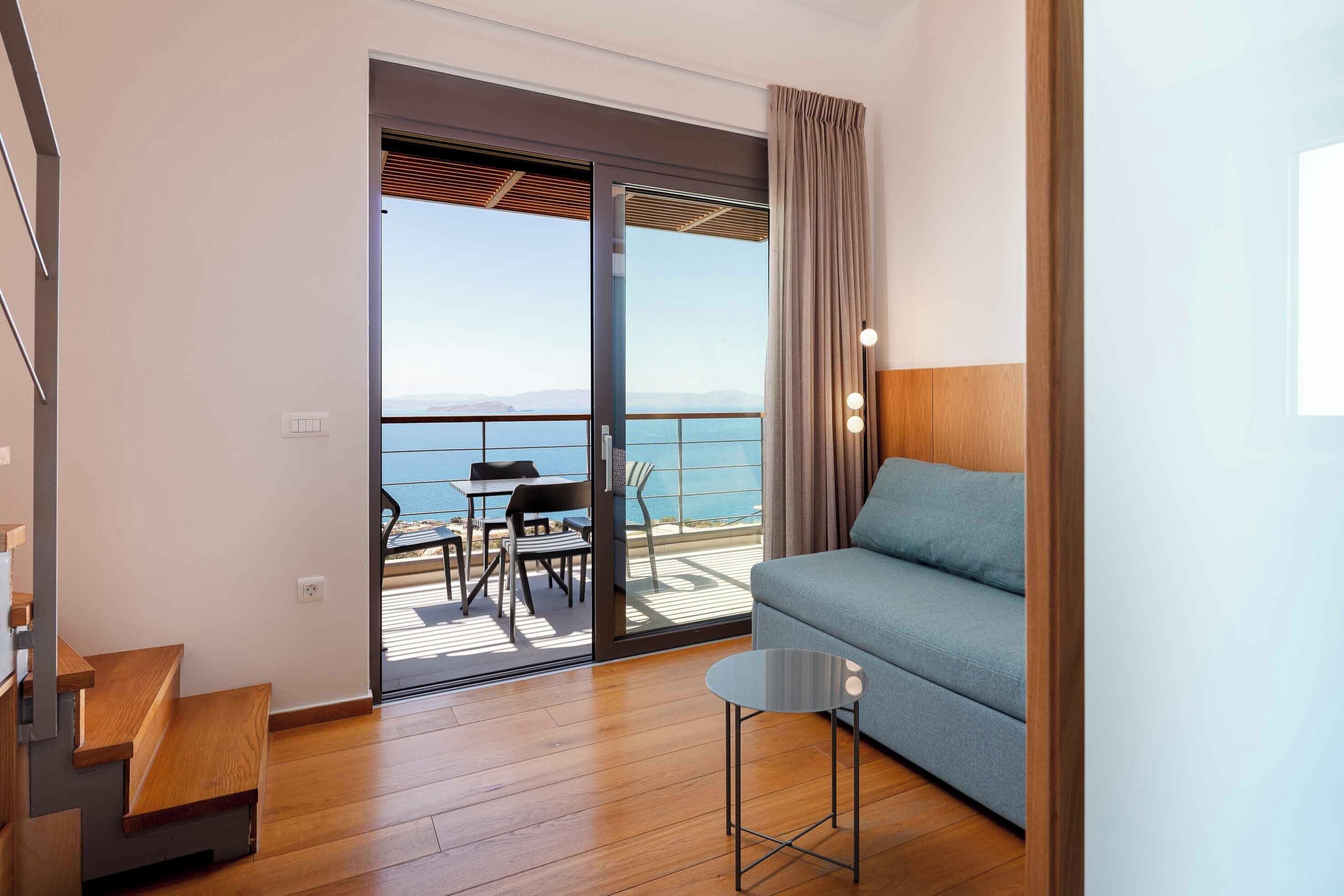 Una habitación moderna con sofá, una mesita y un balcón con mesa y sillas.