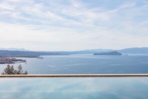 A panoramic view of a coastal city with a clear sky, calm sea, and distant mountains. - Omnia Villas - Holiways Collection (Chania)